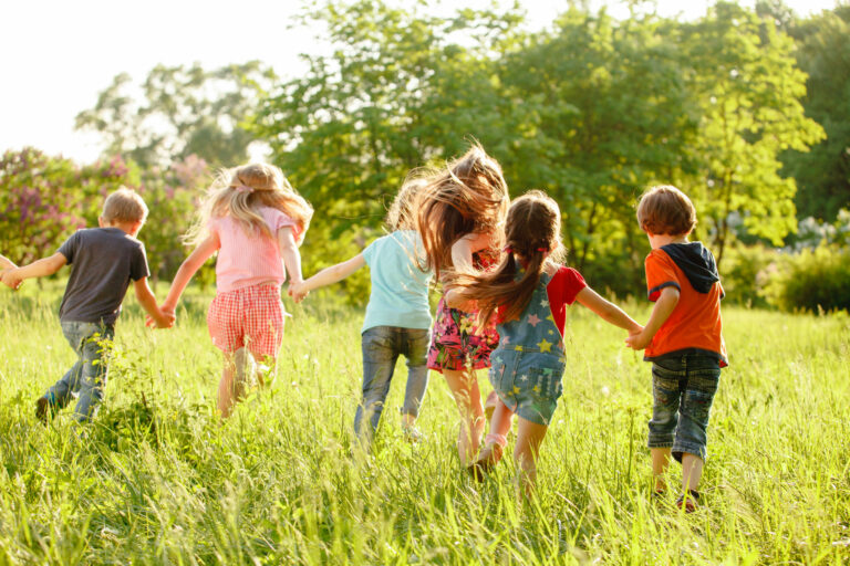 A group of happy children of boys and girls run in the Park on the grass on a Sunny summer day . The concept of ethnic friendship, peace, kindness, childhood